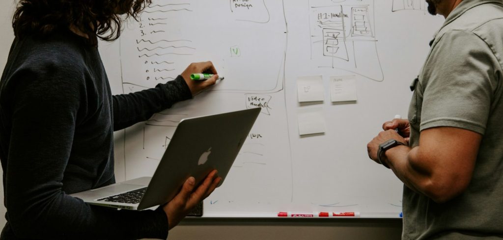 Man wearing gray polo shirt beside dry-erase board